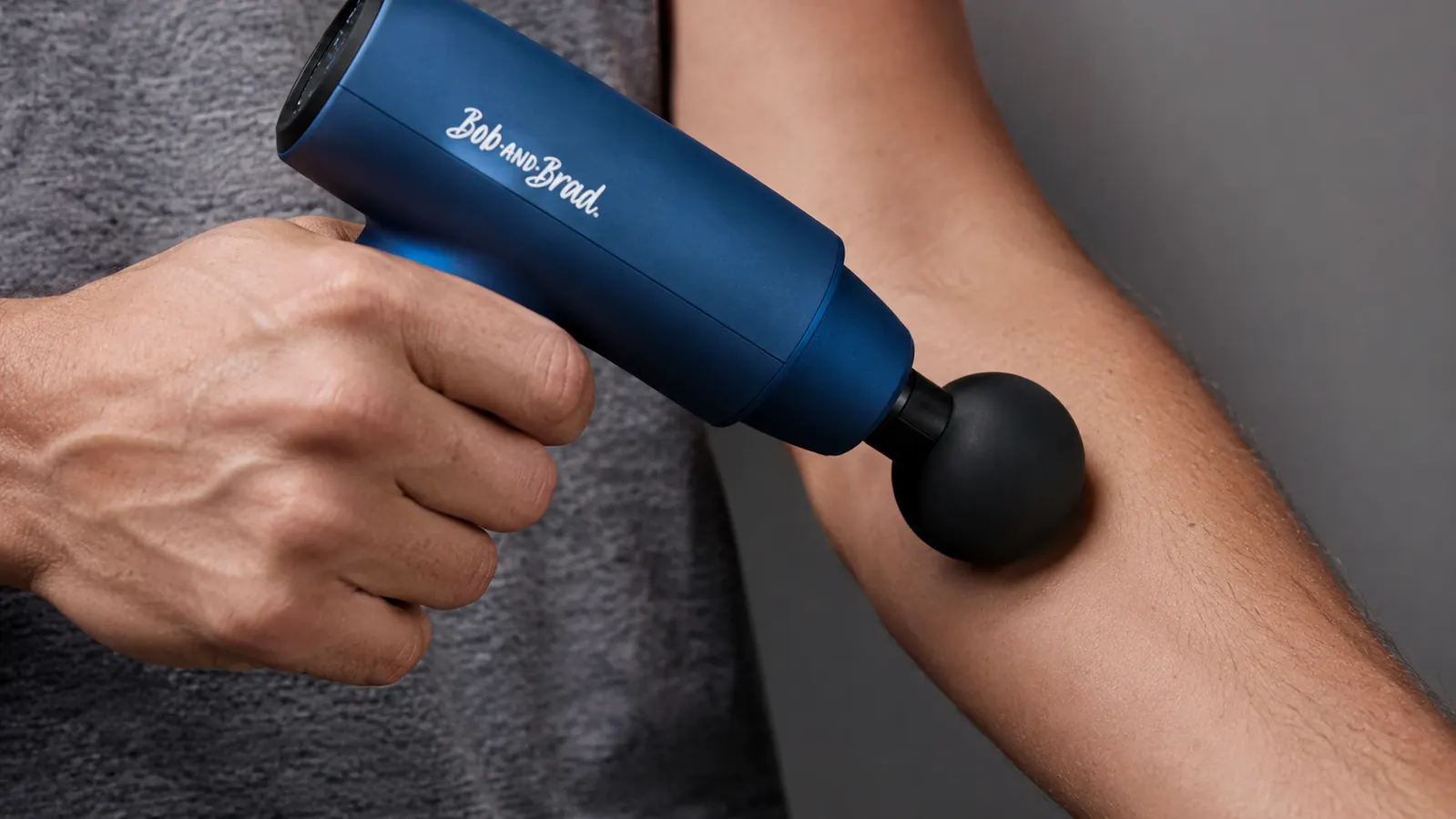 BOB AND BRAD C2 massage gun held in one hand against a forearm showing the device in use