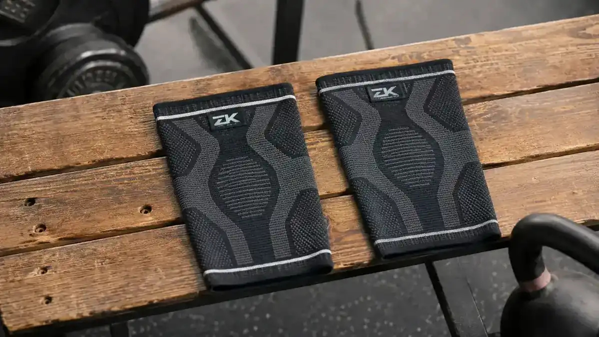 Two knee sleeves side by side on a gym bench, one dark and one lighter colored