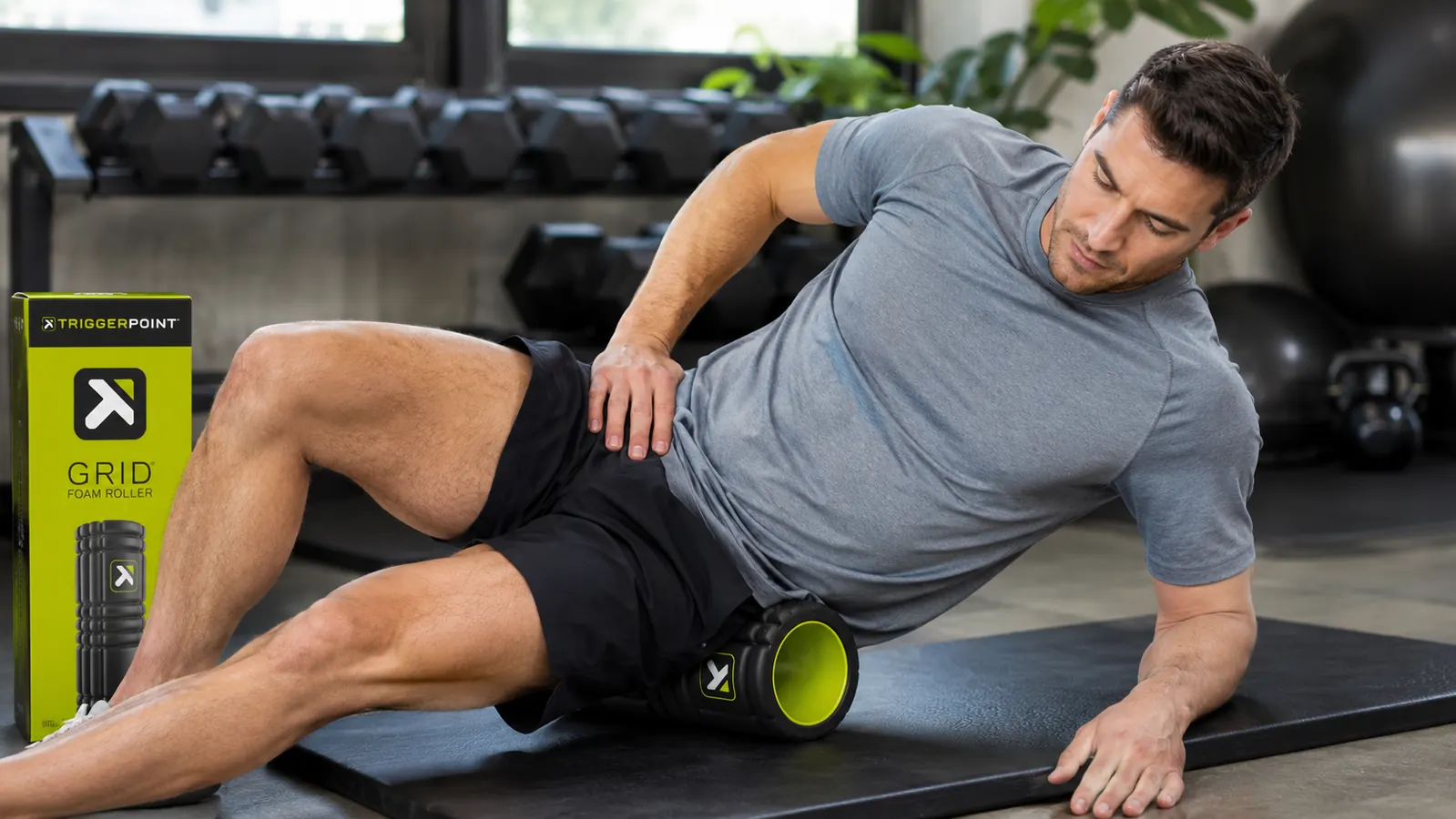 Man foam rolling his quad on a gym mat with the TriggerPoint CORE roller