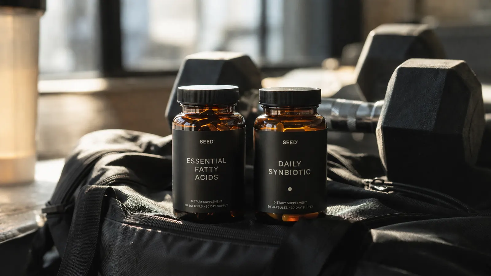 Two tart cherry supplement bottles on a gym bag with a weight rack in the background